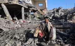 A Palestinian man carries items he salvaged from a house targeted in an Israeli strike at the Nuseirat camp for refugees in the central Gaza Strip on May 24, 2025. (Eyad Baba/AFP)