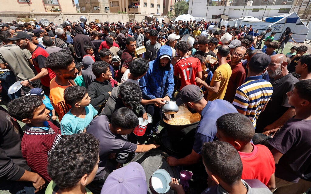 Palestinians gather to receive a hot meal at a food distribution point in the Nuseirat refugee camp in the central Gaza Strip on May 24, 2025. (Eyad BABA / AFP)