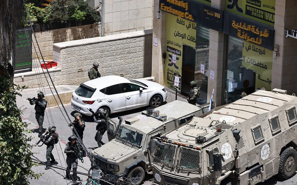 Israeli troops take positions outside a currency exchange shop in Ramallah on May 27, 2025. (Zain JAAFAR / AFP)