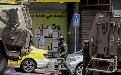 Israeli troops storm a currency exchange shop next to signs warning people not to deal with the Gulf exchange company in Hebron in the southern West Bank on May 27, 2025. (HAZEM BADER / AFP)