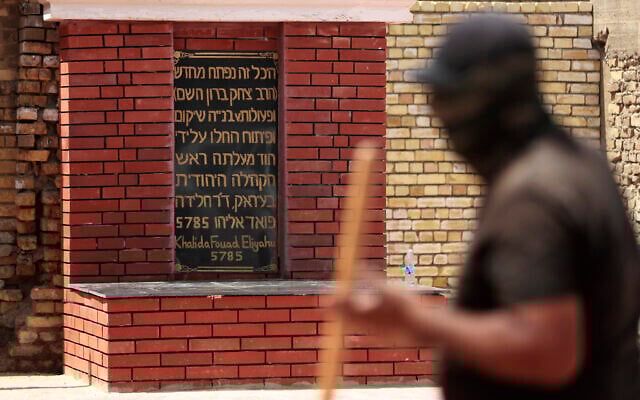 An Iraqi worker walks past a sign in Hebrew during restoration work at the centuries-old shrine of Rabbi Isaac Gaon in central Baghdad's al-Kifah neighborhood on April 21, 2025. (AHMAD AL-RUBAYE / AFP)