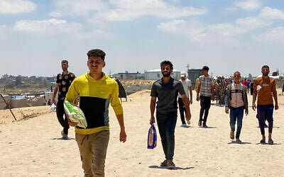 Displaced Palestinians, some carrying a bag of rice, return from an aid distribution center in Khan Younis, in the southern Gaza Strip on May 28, 2025. (AFP)