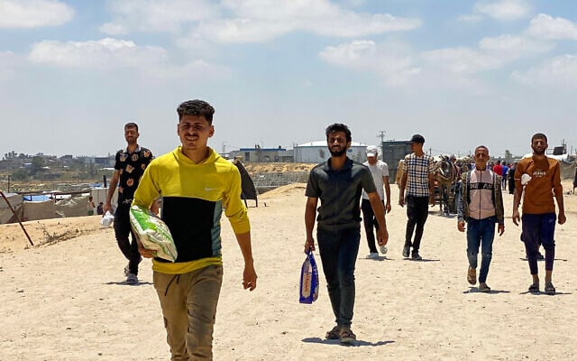 Displaced Palestinians, some carrying a bag of rice, return from an aid distribution center in Khan Younis, in the southern Gaza Strip on May 28, 2025. (AFP) Displaced Palestinians, some carrying a bag of rice, return from an aid distribution center in Khan Younis, in the southern Gaza Strip on May 28, 2025. (AFP)