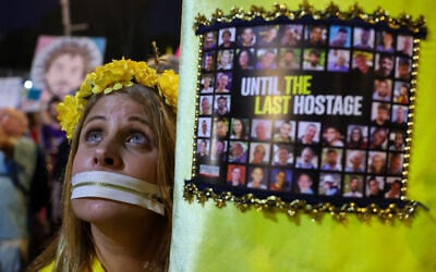 A demonstrator wearing a gag on her mouth holds portraits of the hostages held in the Gaza Strip, at a protest in front of the Defense Ministry in Tel Aviv on May 31, 2025. (Jack Guez/AFP)