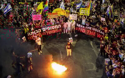 Demonstrators set fire to placards during an anti-government protest calling for action to secure the release of hostages held captive in Gaza, outside the Defense Ministry in Tel Aviv on May 31, 2025. (Jack Guez/AFP)