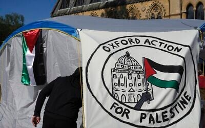 A pro-Palestinian student walks in a tent outside the Pitt Rivers Museum in Oxford, England, Thursday, May 9, 2024. (AP Photo/Kin Cheung)