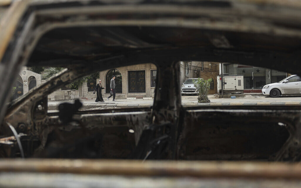 People near a car that was burned during clashes between members of the minority Druze sect and pro-government fighters, in the town of Sahnaya, south of Damascus, Syria, May 1, 2025. (AP Photo/Ghaith Alsayed)