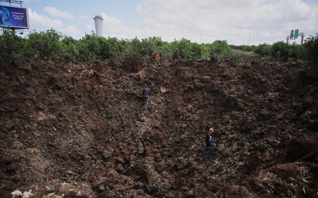 Security forces inspect a crater at the site where a missile fired from Yemen hit an area of Ben Gurion Airport, May 4, 2025 (AP Photo/Ohad Zwigenberg)