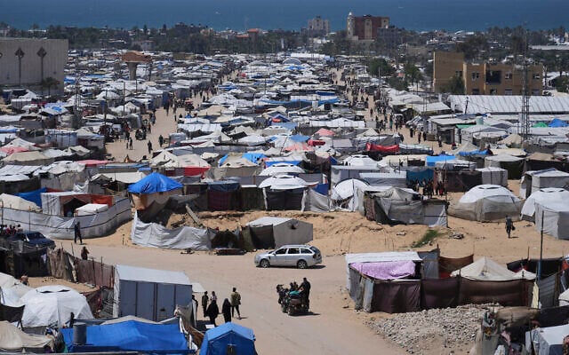 Displaced Palestinians walk through a makeshift tent camp in the Muwasi area of Khan Younis, in the Gaza Strip, on May 5, 2025. (AP Photo/Abdel Kareem Hana)