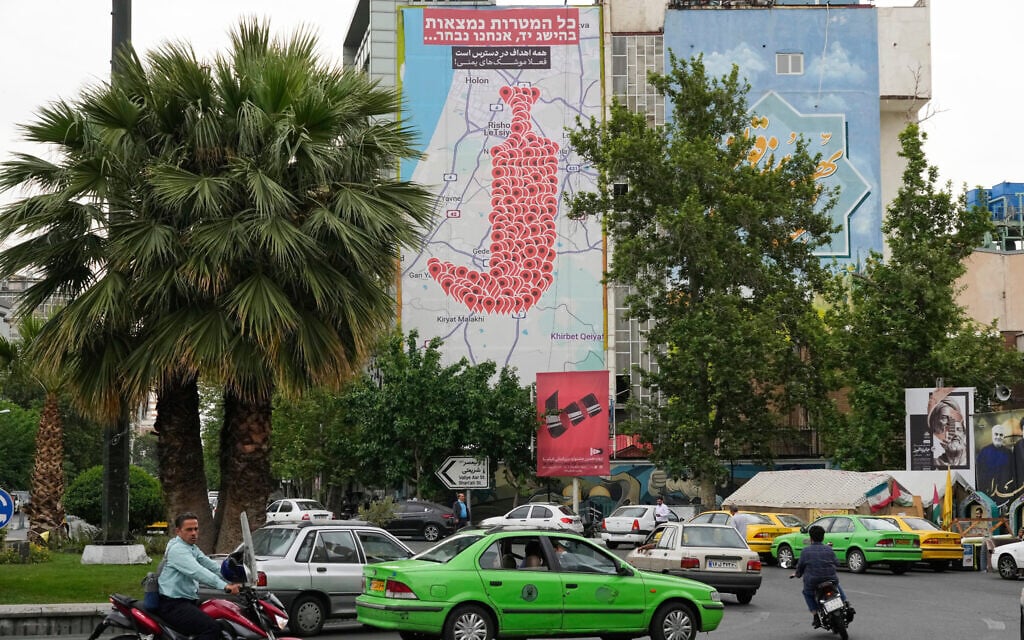 Vehicles and motorcycles drive past an anti-Israel banner apparently showing the symbols for rocket sirens in Israel as a Yemeni dagger (jambiya) with writing in Farsi reading: All targets are within range, Yemeni missiles for now!' and in Hebrew 'All targets are within reach, we will choose,' at the Felestin (Palestine) Sq. in downtown Tehran, Iran, May 5, 2025. (AP Photo/Vahid Salemi)