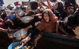 Palestinians struggle to obtain donated food at a community kitchen in Khan Younis, in the southern Gaza Strip, Friday, May 9, 2025. (AP Photo/Abdel Kareem Hana)