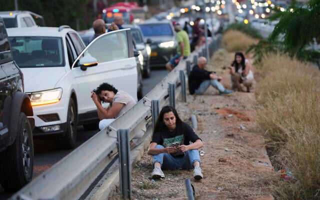 People take cover on the side of a highway as a siren sounds a warning following a missile that was launched from Yemen, in Tel Aviv, Israel, May 13, 2025. (AP Photo/Ohad Zwigenberg)