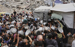 Palestinians struggle to get donated food at a community kitchen in Jabalia, northern Gaza Strip, Thursday, May 15, 2025. (AP Photo/Jehad Alshrafi)