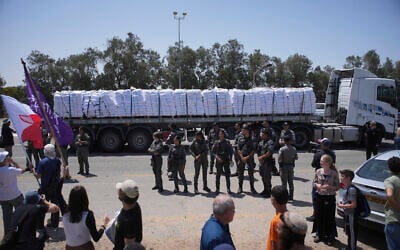 A truck loaded with humanitarian aid for the Gaza Strip makes its way to the Kerem Shalom crossing as Border Police officers prevent activists from blocking the road in southern Israel, May 21, 2025. (AP/Ohad Zwigenberg)