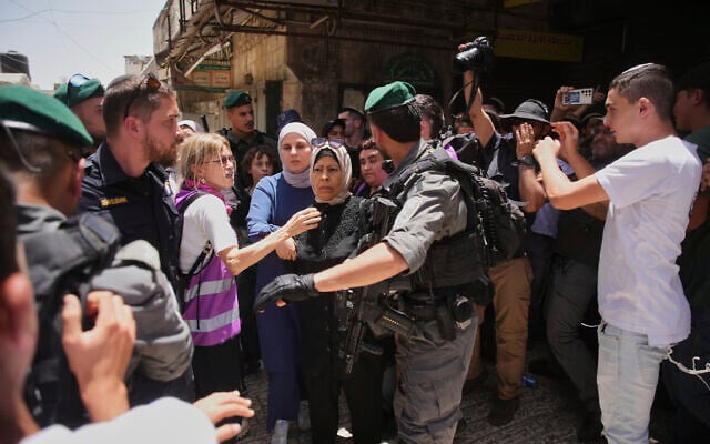 Israeli police officers escort Palestinian women while right wing Israelis marking Jerusalem Day chant racist chants in Jerusalem's Old City, May 26, 2025. (AP Photo/Ohad Zwigenberg)