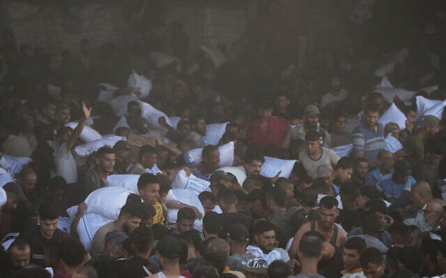 Palestinians carry bags of flour after storming a UN World Food Program warehouse in Zawaida, Central Gaza Strip, on Wednesday, May 28, 2025. (AP Photo/Abdel Kareem Hana)