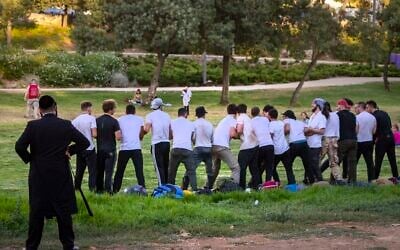 An ultra Orthodox man looks on as teenagers train for the military in Jerusalem on July 26, 2019. (Olivier Fitoussi/Flash90)