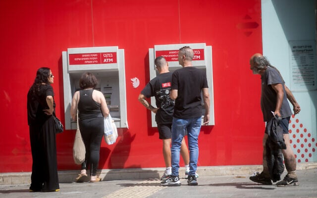 A homeless man walks by Israelis in line to take out money at an ATM in Tel Aviv on September 30, 2024. (Miriam Alster/FLASH90) A homeless man walks by Israelis in line to take out money at an ATM in Tel Aviv on September 30, 2024. (Miriam Alster/FLASH90)