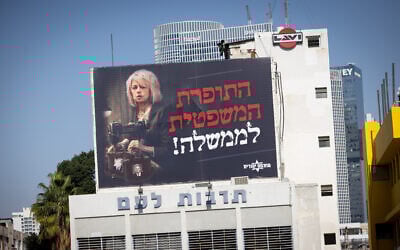 A billboard showing Attorney General Gali Baharav-Miara accuses her of spinning tales against the government, in Tel Aviv, December 6, 2024. The billboard dubs Baharav-Miara 'judicial seamstress to the government,' in a Hebrew-language pun on her office's name. (Miriam Alster/Flash90)