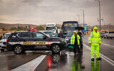 People wait on the blocked Highway 90 in the Negev Desert, after it was flooded due to heavy rains on May 4, 2025. (David Cohen/Flash90)