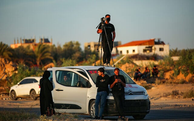Members of the press wait for a Red Cross convoy after Hamas's release of American-Israeli hostage Edan Alexander, on Salah al-Din Street, east of Deir al-Balah, in the central Gaza Strip, May 12, 2025. (Ali Hassan/Flash90)