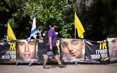 People walk by posters of hostage Edan Alexander on May 12, 2025. (Miriam Alster/Flash90)