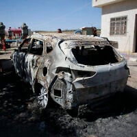 Palestinians examine a burned vehicle set on fire by unknown attackers overnight, in the Masoudiya area, north of the West Bank city of Nablus, May 16, 2025. (Nasser Ishtayeh/Flash90)