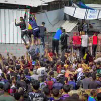 Displaced Palestinians reach out for bread being distributed through a bakery window in Nuseirat Refugee Camp, in the central Gaza Strip, May 22, 2025. (Ali Hassan/Flash90)