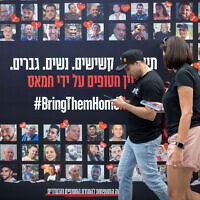 People walk past posters of Israelis who have been and are still held hostage in Gaza, in Tel Aviv, May 21, 2025. (Miriam Alster/Flash90)
