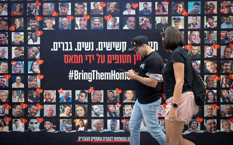 People walk past posters of Israelis who have been and are still held hostage in Gaza, in Tel Aviv, May 21, 2025. (Miriam Alster/Flash90)