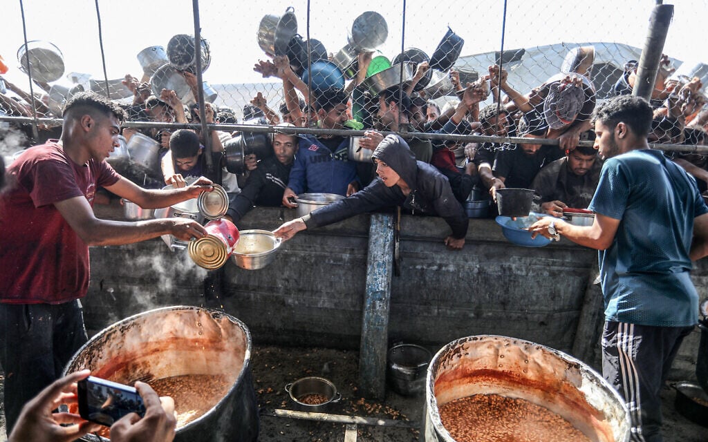 Palestinians receive a hot meal prepared by volunteers, in Khan Younis, in the southern Gaza Strip, May 30, 2025 (Abed Rahim Khatib/Flash90)