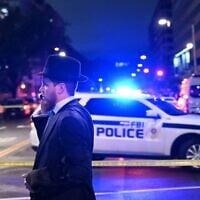 A man, standing behind police tape, talks on his cell phone outside the Capital Jewish Museum following a shooting that killed two people, in Washington, DC, in the early hours of May 22, 2025. (Alex Wroblewski/AFP via Getty Images via JTA)