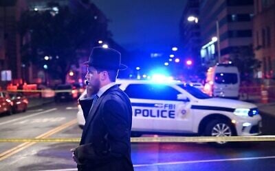 A man, standing behind police tape, talks on his cell phone outside the Capital Jewish Museum following a shooting that killed two people, in Washington, DC, in the early hours of May 22, 2025. (Alex Wroblewski/AFP via Getty Images via JTA)