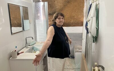 Shula Giladi stands in the bathroom of her house in Shtula, damaged during the Israel-Hezbollah war on May 23, 2025. (Diana Bletter/Times of Israel)