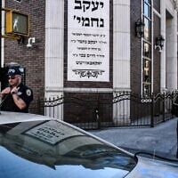A member of the New York Police Department patrols in front of the synagogue Congregation Bais Yaakov Nechamia Dsatmar on October 13, 2023. (Stephanie Keith/Getty Images)