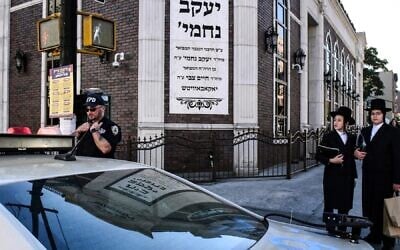 A member of the New York Police Department patrols in front of the synagogue Congregation Bais Yaakov Nechamia Dsatmar on October 13, 2023. (Stephanie Keith/Getty Images)