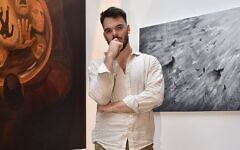 Freed hostage Andrey Kozlov poses in New York in May 2025 with the artwork he created over the last few months, after his rescue from Hamas captivity in June 2024 (Courtesy)