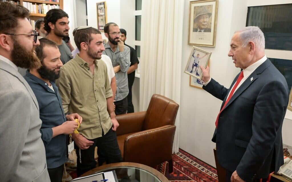 Prime Minister Benjamin Netanyahu, right, meets wounded IDF reservists from the 'Wounded Soldiers for Victory' forum, at his office in Jerusalem, May 12, 2025. Netanyahu is holding up a photo of Ari Spitz, an IDF soldier who lost three limbs while fighting in Gaza. (Maayan Toaf/GPO)