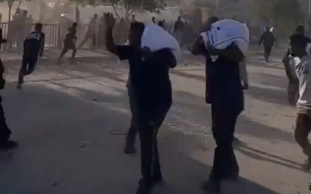People carry sacks of flour as aid trucks are apparently looted in the Khan Younis area on May 31, 2025 (Screen grab used in accordance with Clause 27a of the Copyright Law)