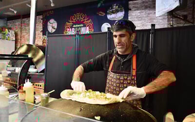 Raif Rashed, an Israeli Druze and the owner of Taboonia, wraps up a pita with labneh in May 2025. (Jackie Hajdenberg/JTA)