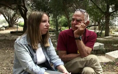 Freed hostages Doron Katz-Asher, left, sits near the grave of her mother Efrat Katz, alongside Efrat's partner, former hostage Gadi Mozes, in Kibbutz Revadim, during an interview broadcast by Channel 12 on May 23, 2025. (Screen capture: Channel 12)