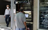 A man withdraws money from an ATM at Sepah Bank in the Iranian capital of Tehran, on June 15, 2022. (Atta Kenare/AFP)