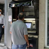 A man withdraws money from an ATM at Sepah Bank in the Iranian capital of Tehran, on June 15, 2022. (Atta Kenare/AFP)