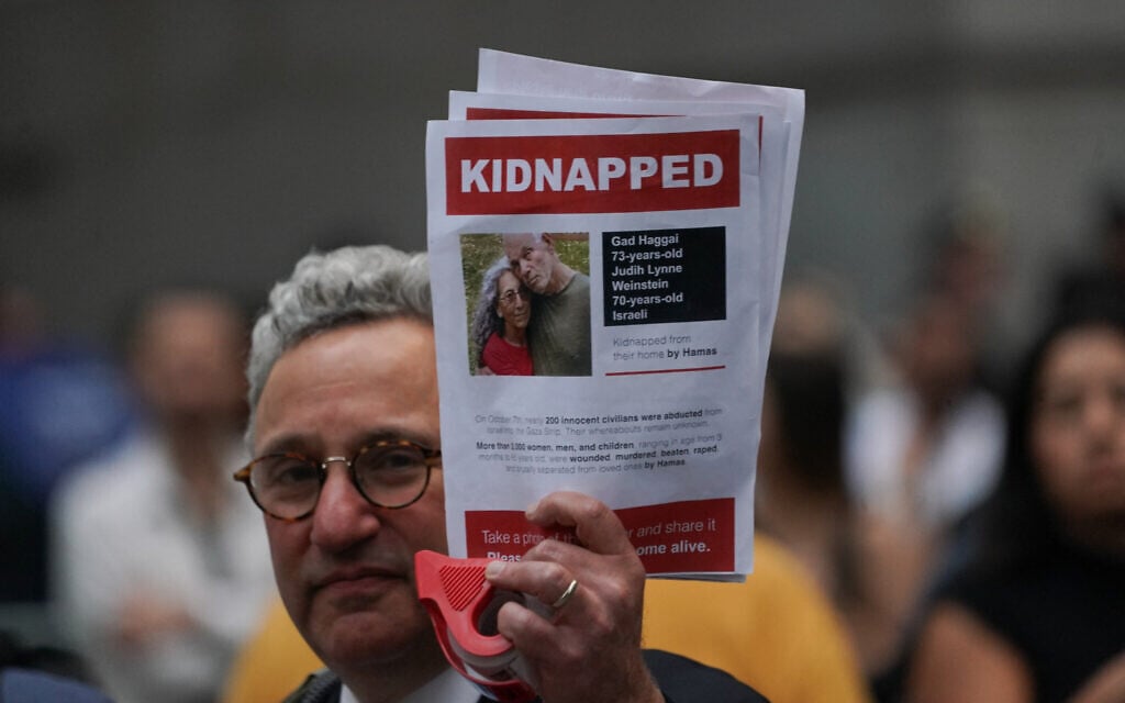 A supporter of Israel holds a picture of kidnapped Israeli hostages Gadi Haggai and Judih Weinstein on October 26, 2023, in New York. (Bryan R. Smith / AFP)