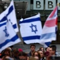Pro-Israel demonstrators hold placards and wave Israeli flags as they take part in a protest outside the BBC headquarters, in London, on February 4, 2024. (HENRY NICHOLLS / AFP)