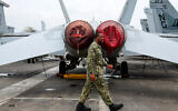 Illustrative: A US Navy officer walks past fighter jets parked on the flight deck of the Nimitz-class aircraft carrier USS Abraham during a media tour in Port Klang, on the outskirts of Kuala Lumpur, on November 26, 2024. (FAZRY ISMAIL / POOL / AFP)