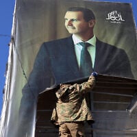 An anti-government fighter tears down a portrait of Syria's then-President Bashar al-Assad in Aleppo, after jihadists and their allies entered the northern Syrian city, on November 30, 2024. (Mohammed AL-RIFAI / AFP)