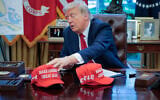 US President Donald Trump adjusts "Make America Great Again" hats as he prepares to sign executive orders in the Oval Office at the White House on April 23, 2025 in Washington, DC. (Chip Somodevilla/Getty Images/AFP)