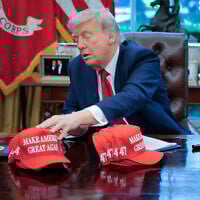 US President Donald Trump adjusts "Make America Great Again" hats as he prepares to sign executive orders in the Oval Office at the White House on April 23, 2025 in Washington, DC. (Chip Somodevilla/Getty Images/AFP)