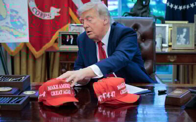 US President Donald Trump adjusts "Make America Great Again" hats as he prepares to sign executive orders in the Oval Office at the White House on April 23, 2025 in Washington, DC. (Chip Somodevilla/Getty Images/AFP)